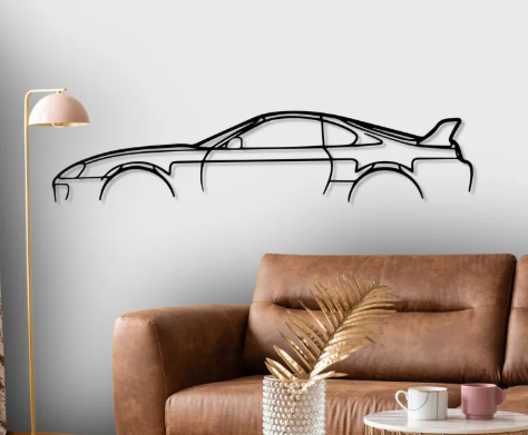 Car-shaped wall decal on a gray wall above a brown sofa with decorative elements.