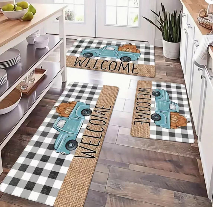 Set of three decorative doormats with a blue truck design on a wooden floor.