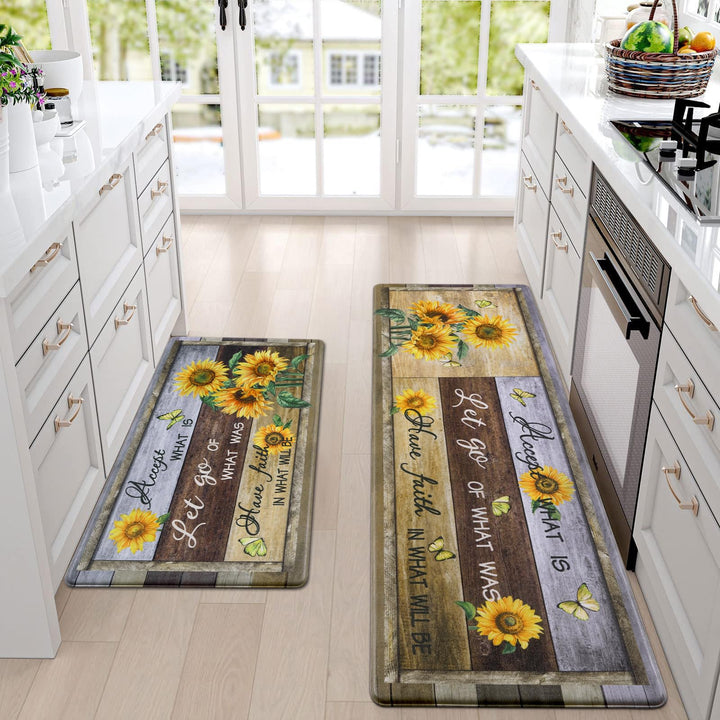 Two decorative kitchen mats with sunflower designs and inspirational quotes on a light wood floor.
