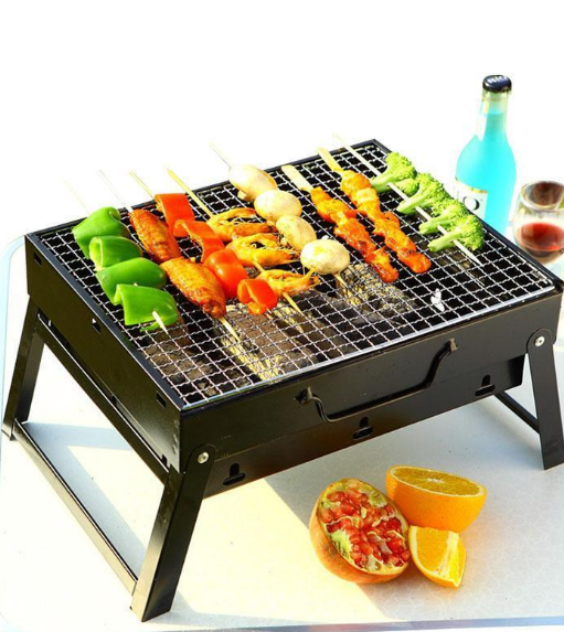 Portable grill with skewered vegetables and a bottle of beer on a white background